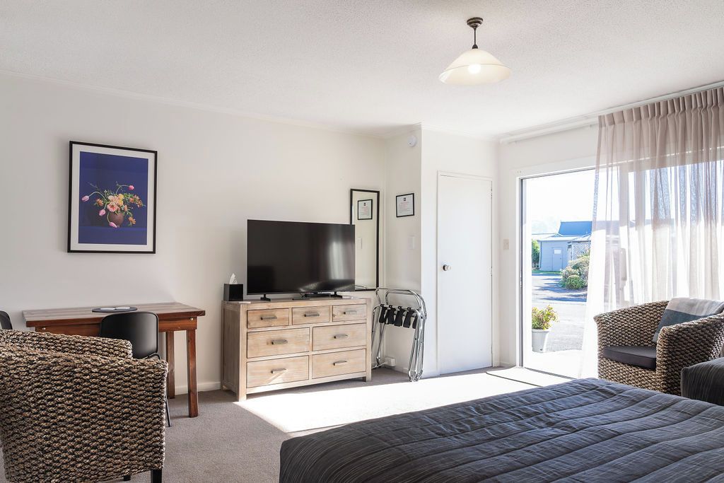 Un dormitorio con cama, televisor, escritorio y silla.