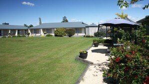 A well-maintained lawn, a covered seating area, and a building with multiple windows and a flat roof. - Mount Hutt Motels (Methven)