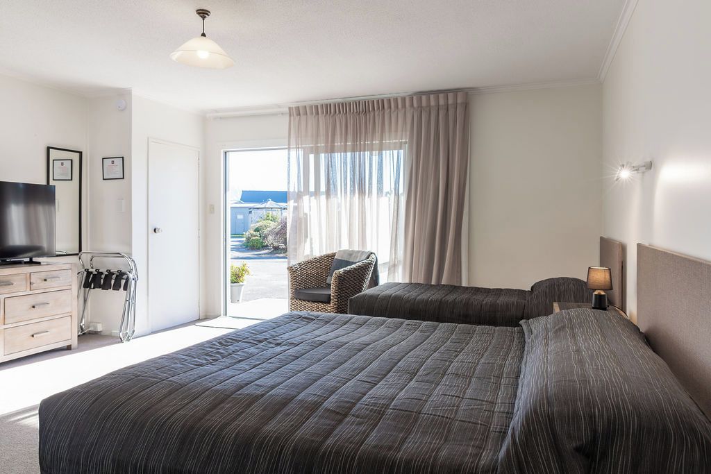 Une chambre d’hôtel avec deux lits, une télévision, un bureau et une chaise.
