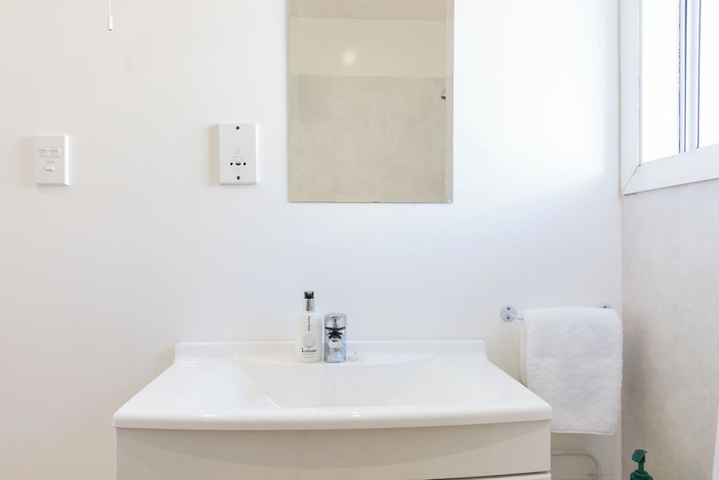 Ein Badezimmer mit einem weißen Waschbecken, einem Spiegel und einem Handtuchhalter.