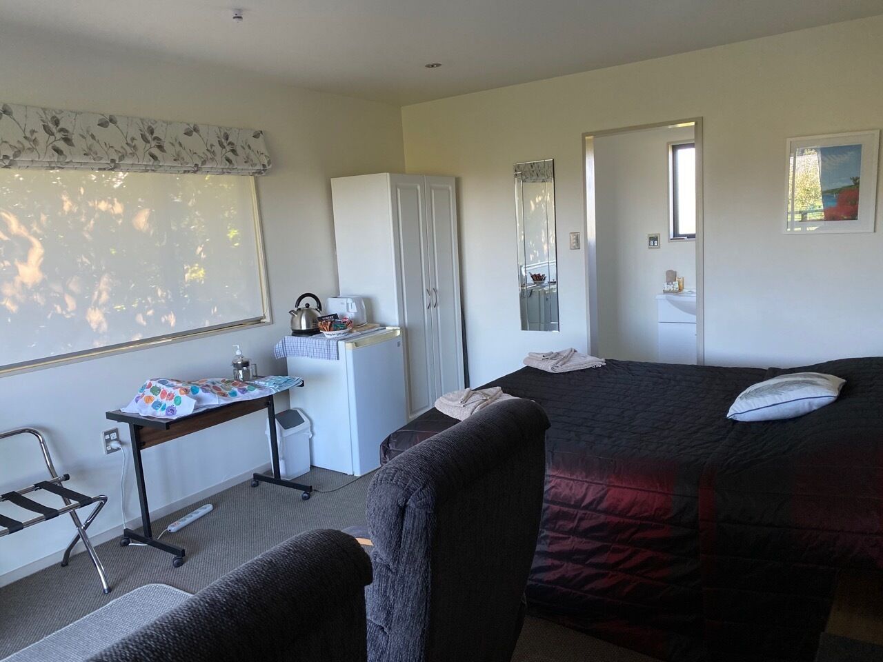 Une chambre d’hôtel comprenant un lit, un bureau, une chaise, une armoire, un miroir et une fenêtre.