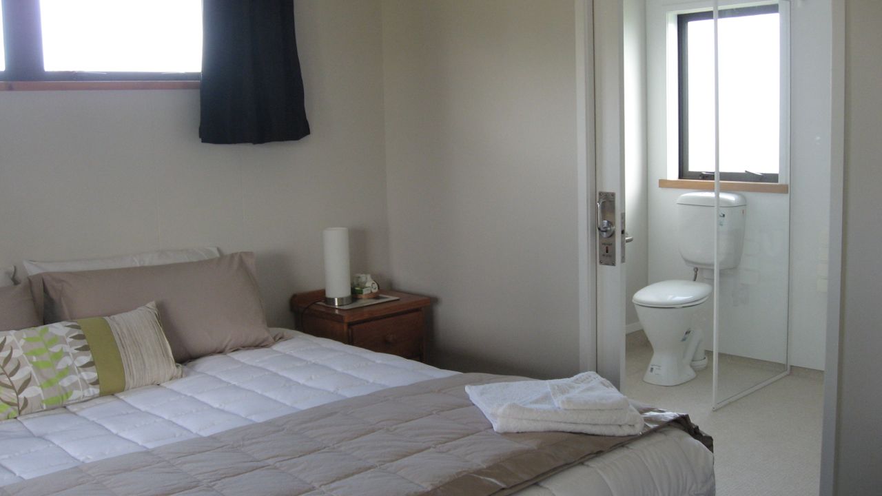 A bedroom with a bed, bedside table, and a view of the bathroom.