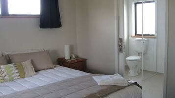 A bedroom with a bed, bedside table, and a view of the bathroom.