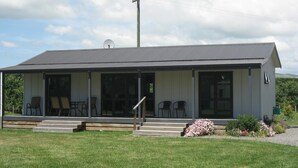 A single-story building with a covered porch, multiple chairs, and a small garden area. - Bluebell Lodge And Cottage (Hastings)