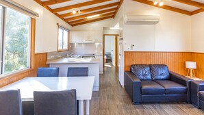 Une cuisine moderne avec des meubles blancs, un coin repas avec une table et des chaises blanches, et un canapé en cuir.
