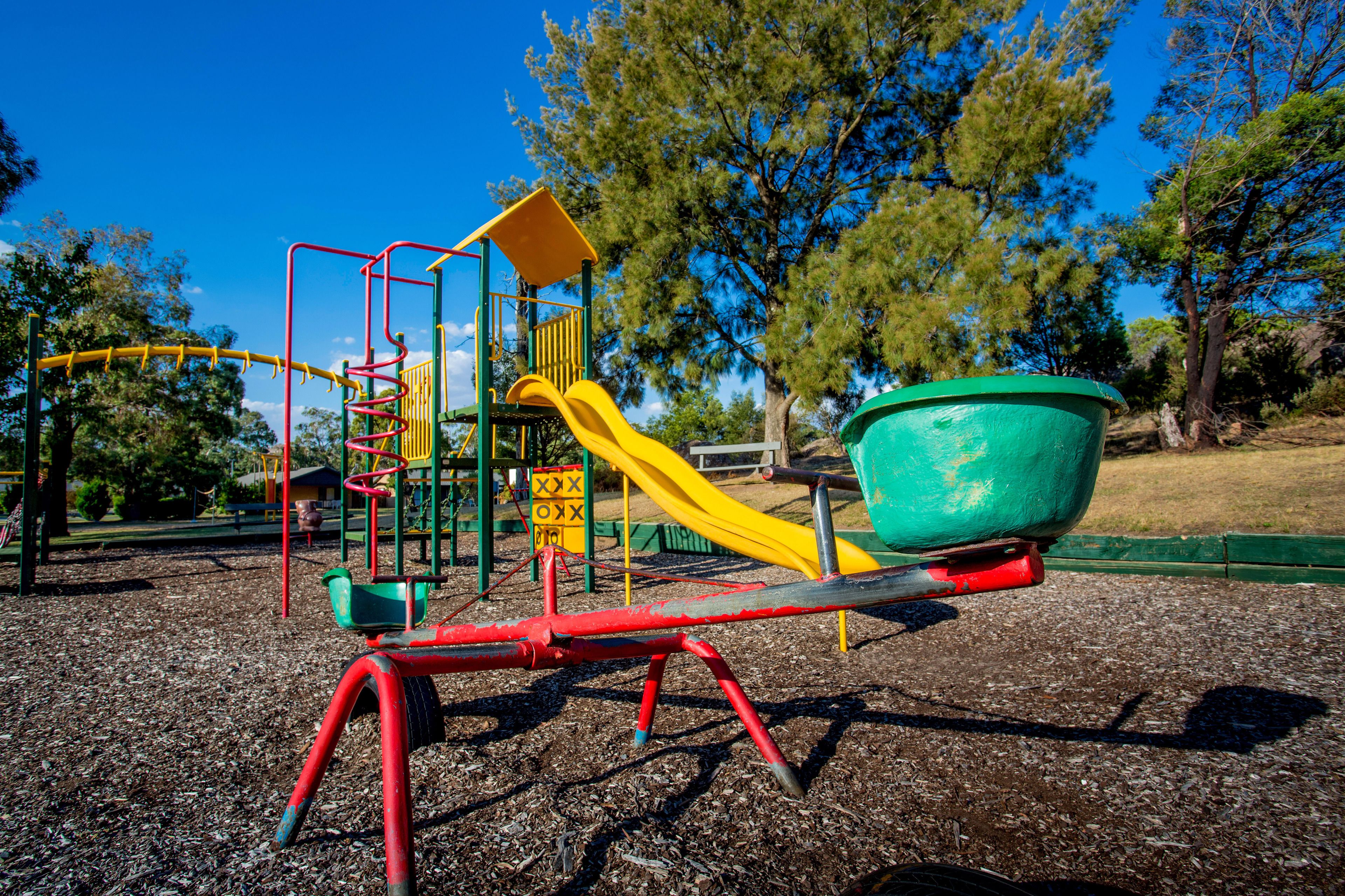 Ein Spielplatz mit Wippe, Rutsche und Klettergerüst.