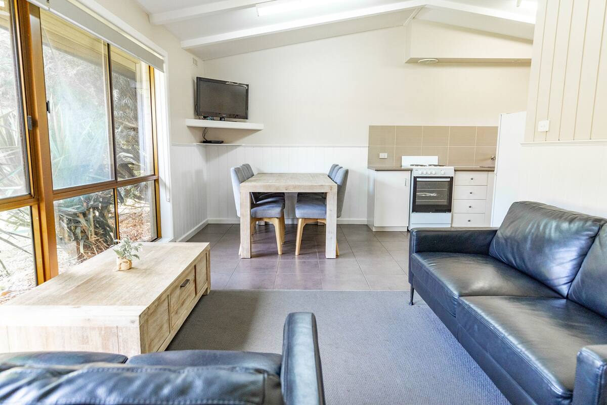 A compact living space with a dining area, a sofa, and a kitchen.