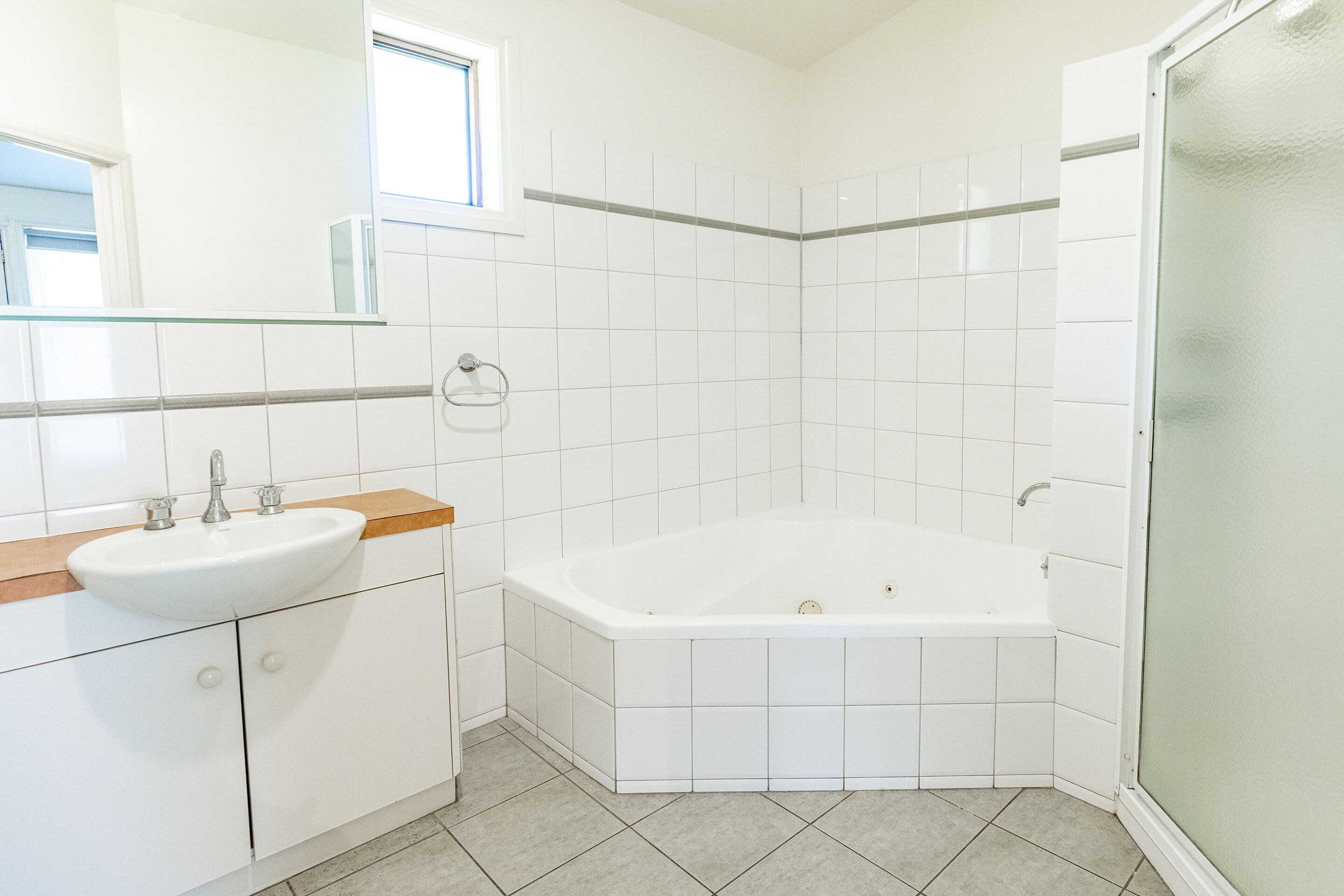 A modern bathroom with a white sink, vanity, and bathtub.