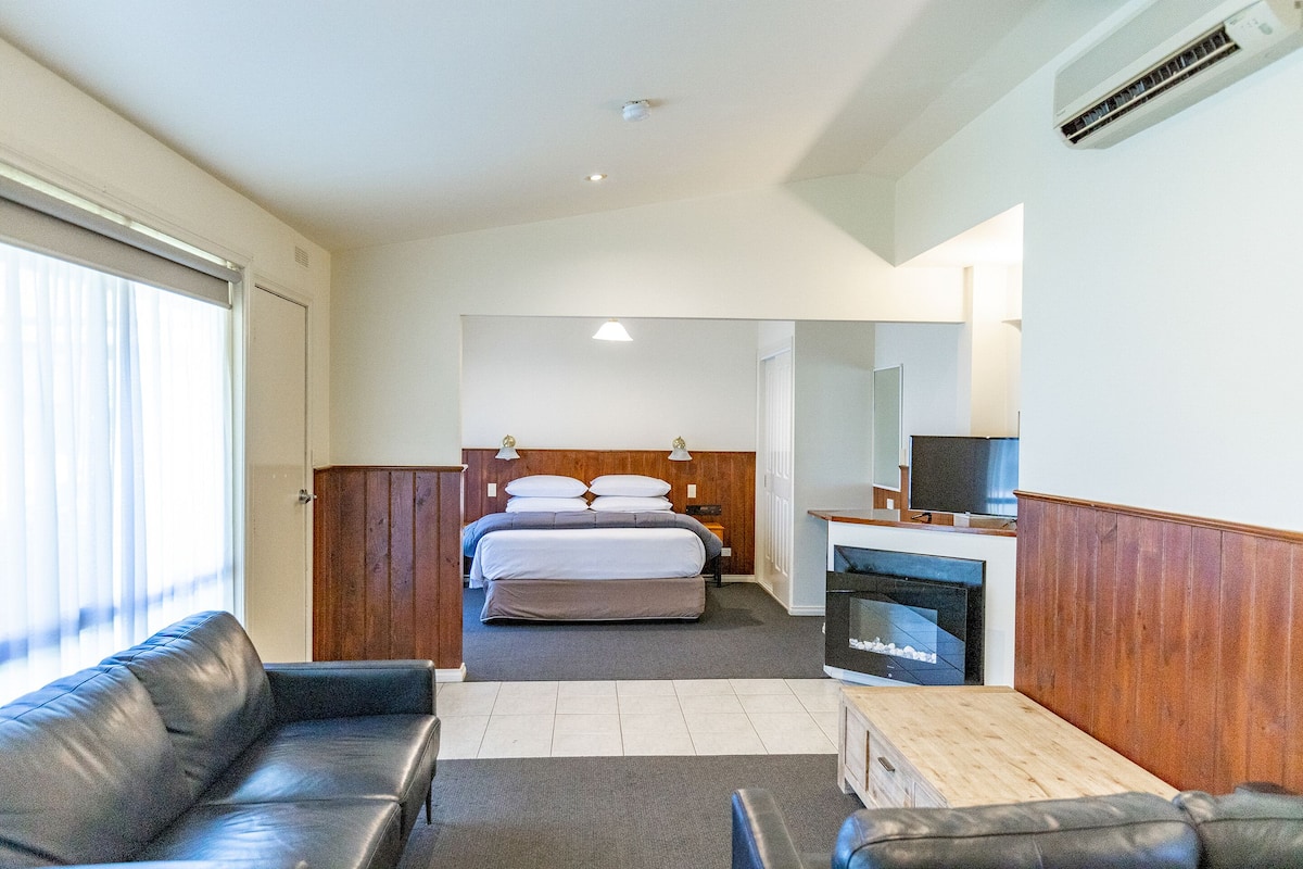 A hotel room with a bed, a TV, a fireplace, and a sofa.