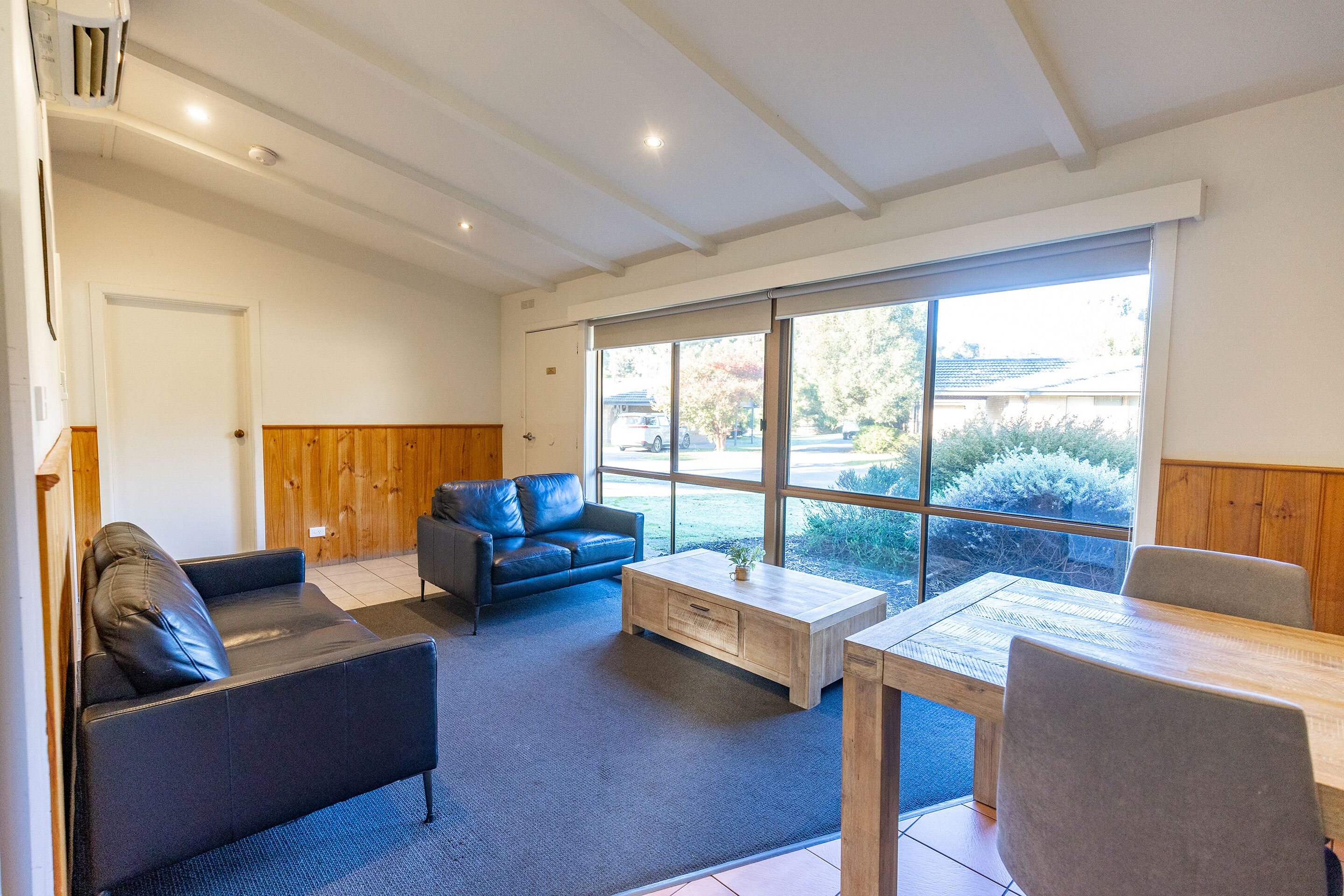 A modern living room with a sofa, coffee table, and dining table.