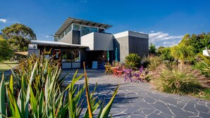 Une maison moderne dotée d’un patio en pierre, d’un espace salon extérieur et d’une végétation luxuriante.