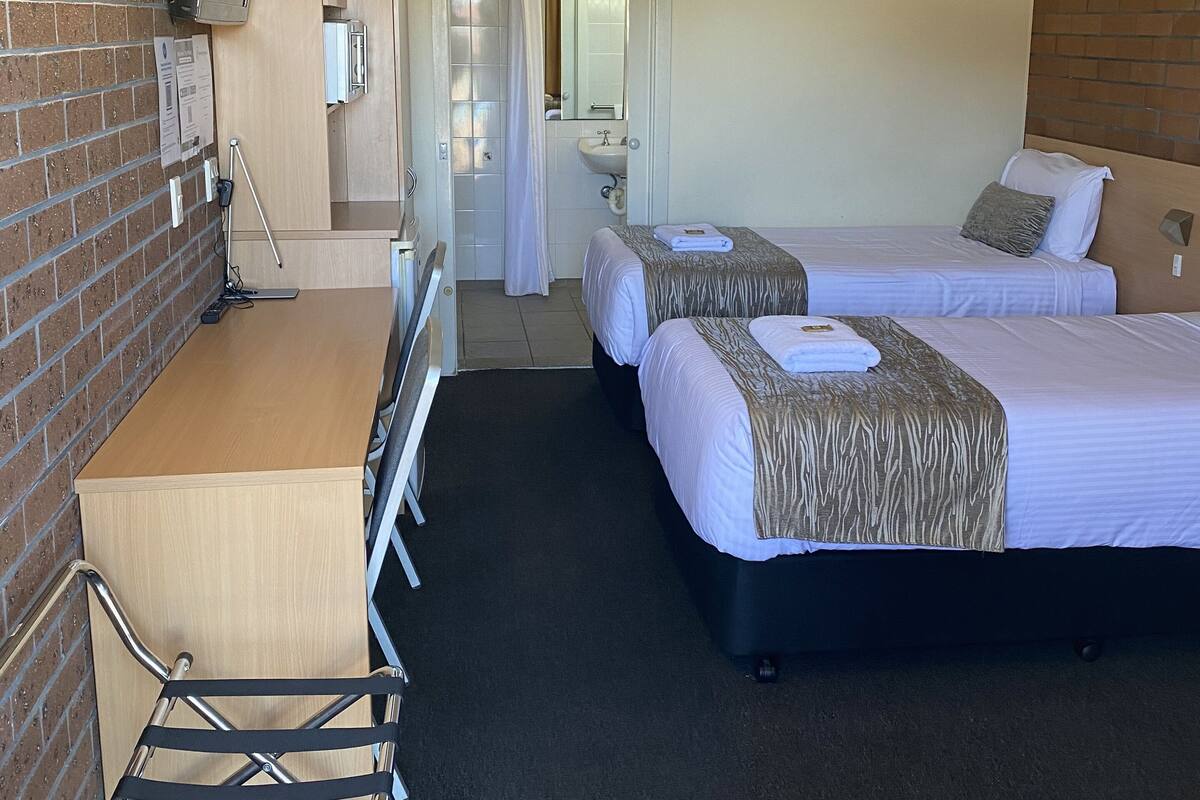 Une chambre d’hôtel avec deux lits, un bureau, une chaise, une douche et une salle de bain.