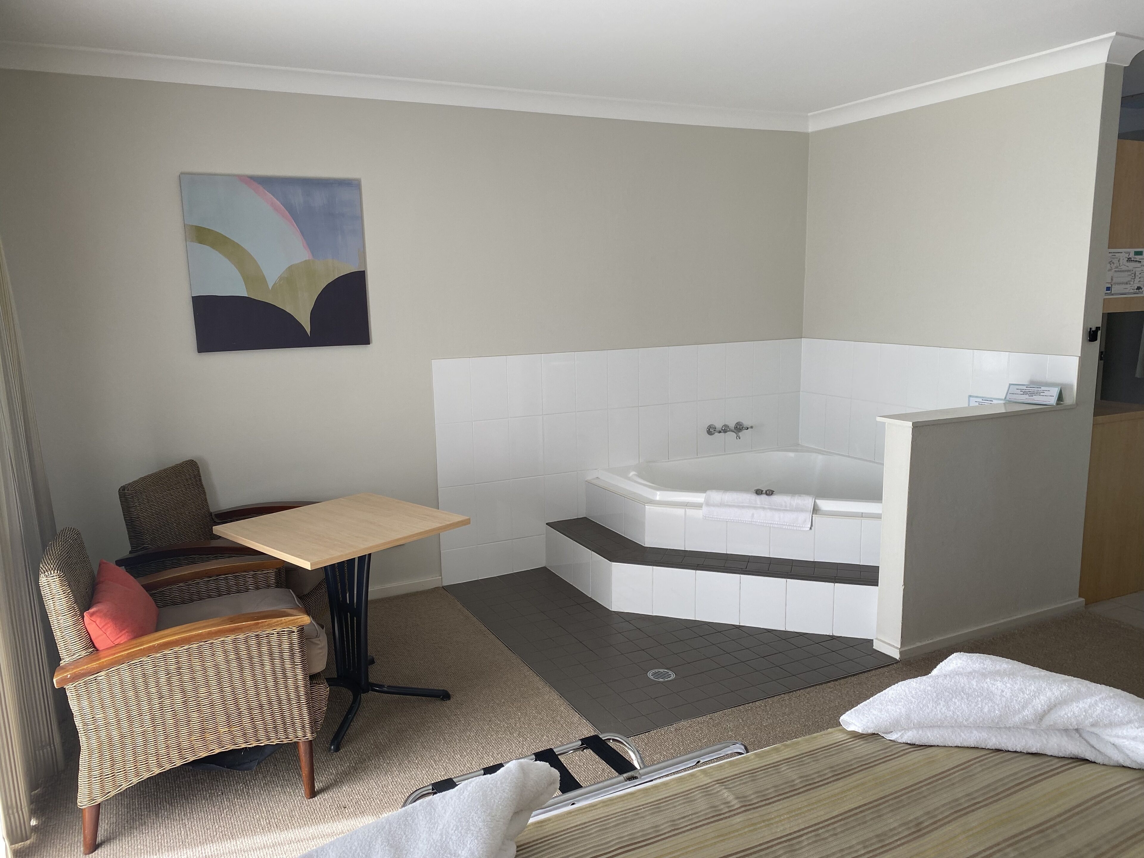 A modern bathroom with a bathtub, a small table, and a chair.