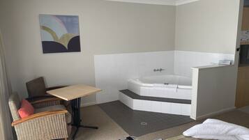 A modern bathroom with a bathtub, a small table, and a chair.