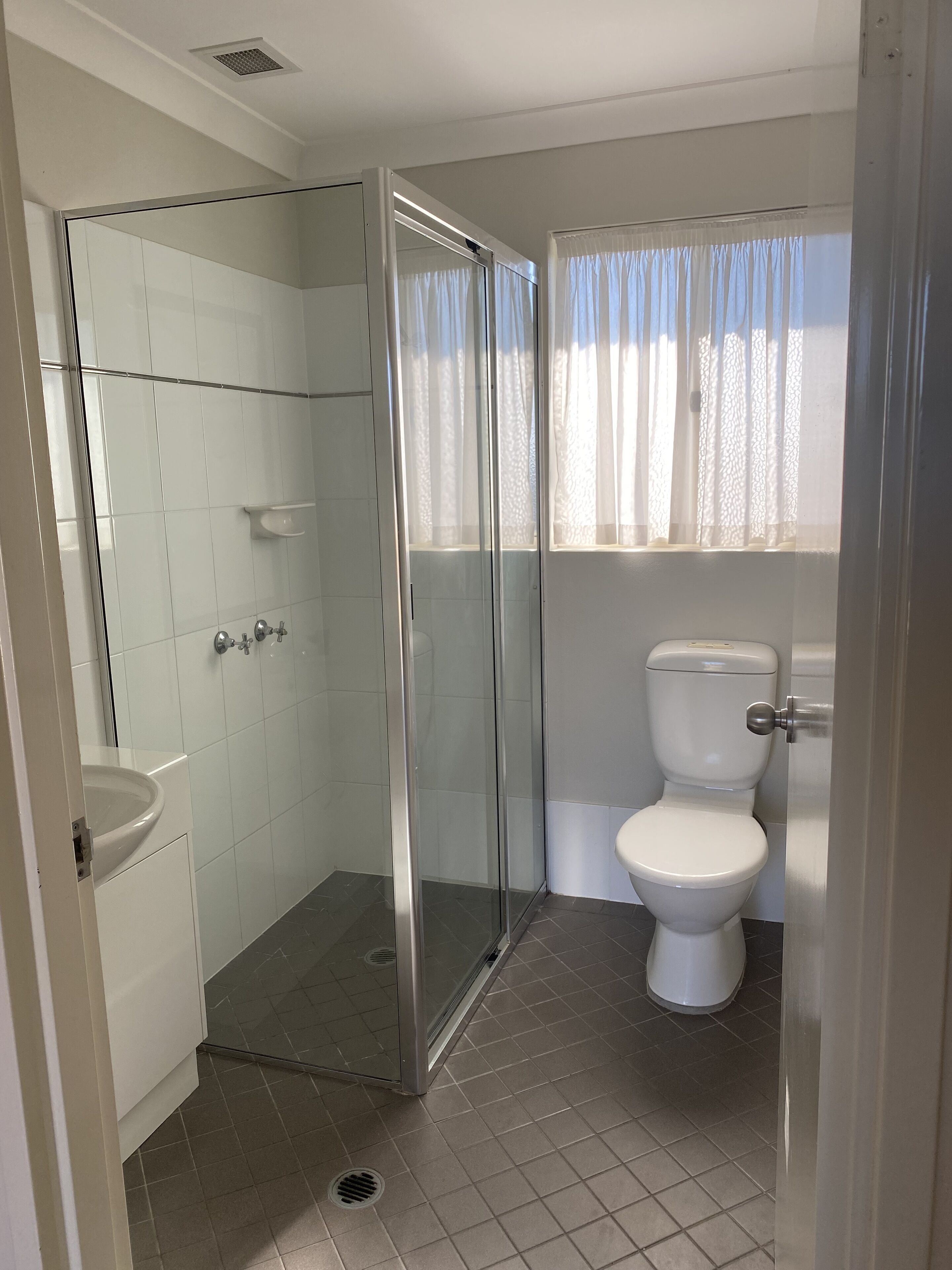A bathroom with a glass-enclosed shower, a sink, and a toilet.