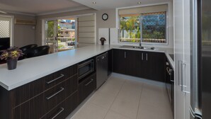 A modern kitchen with dark cabinetry, a white countertop, and a large window.