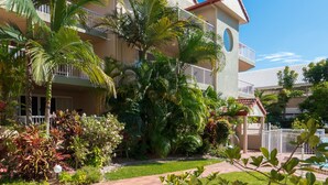 A hotel with a well-maintained garden, a paved walkway, and a pool area.