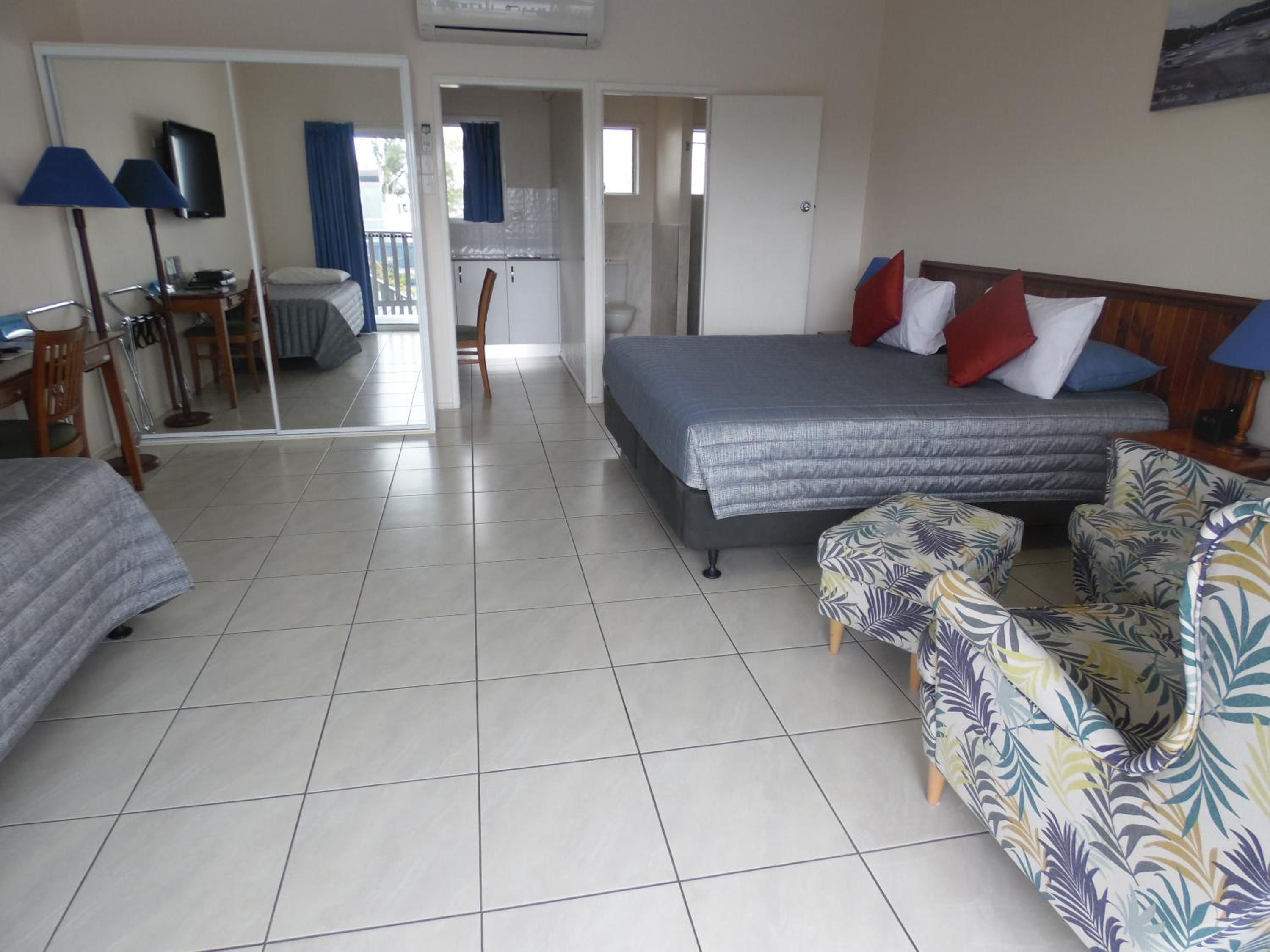 Una habitación de hotel con cama, sofá, escritorio con silla, televisión y ventana.