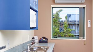 A kitchen with a stainless steel sink, a microwave, and a window with a view of buildings and trees.