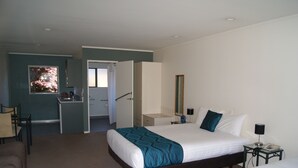 A hotel room with a bed, bedside table, and a desk with a chair.