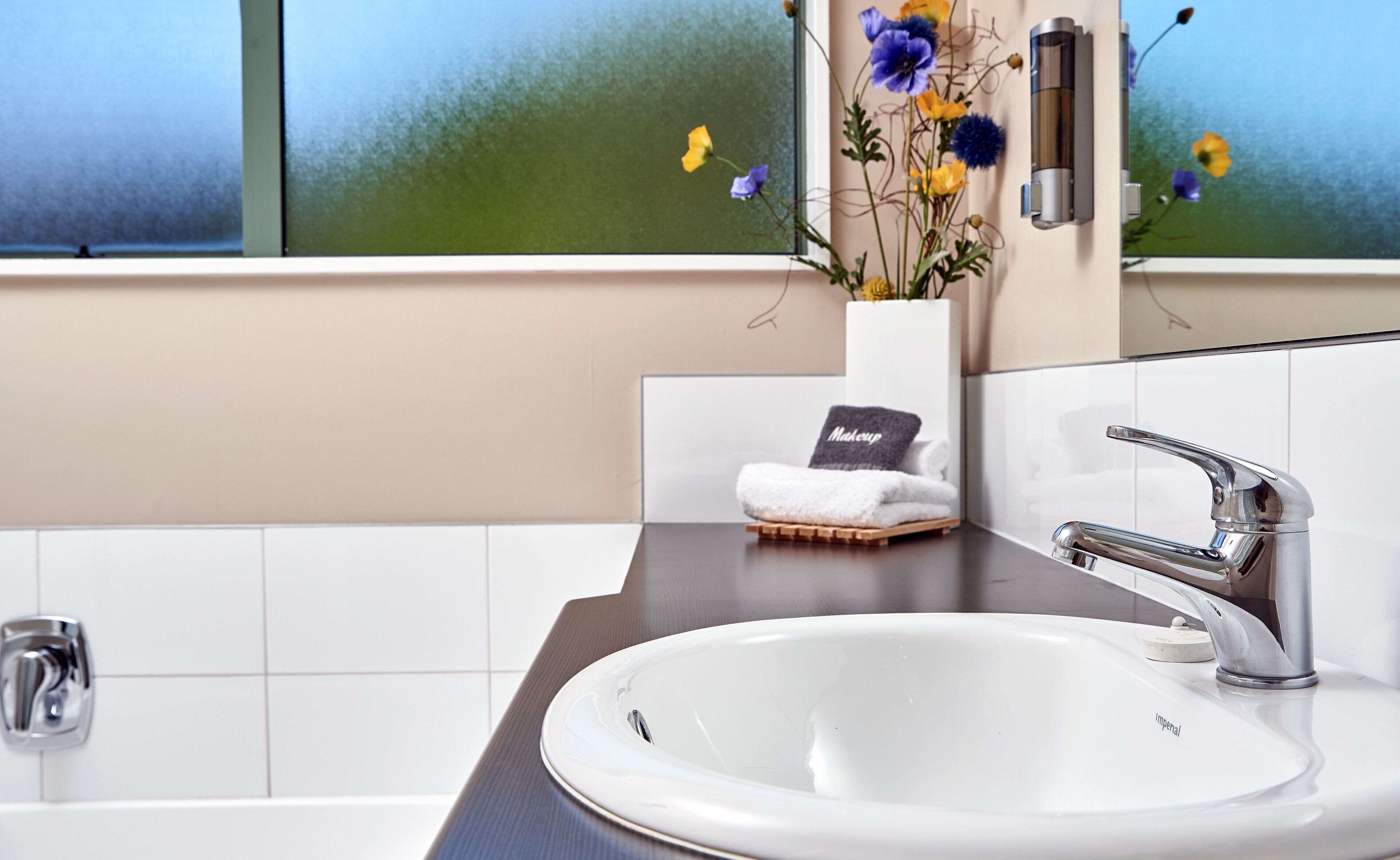 A bathroom with a white sink, chrome faucet, and a towel rack with a towel.