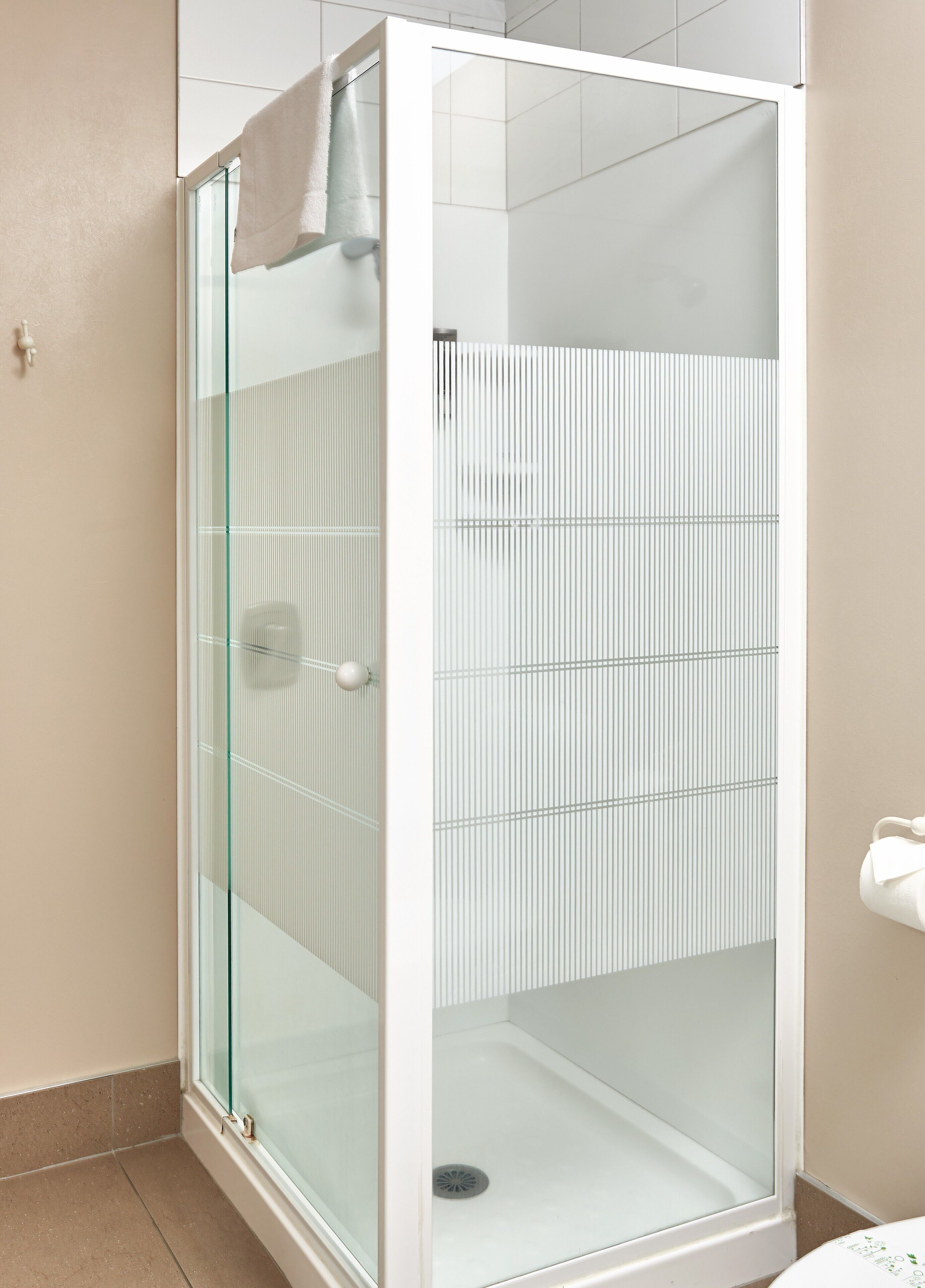 A modern bathroom with a glass-enclosed shower, a white sink, and a beige tiled floor.