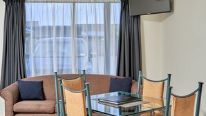 A modern room with a glass table, cushioned chairs, and a sofa.