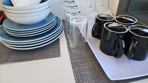 Una mesa puesta con platos apilados, tazones, vasos y tazas negras.