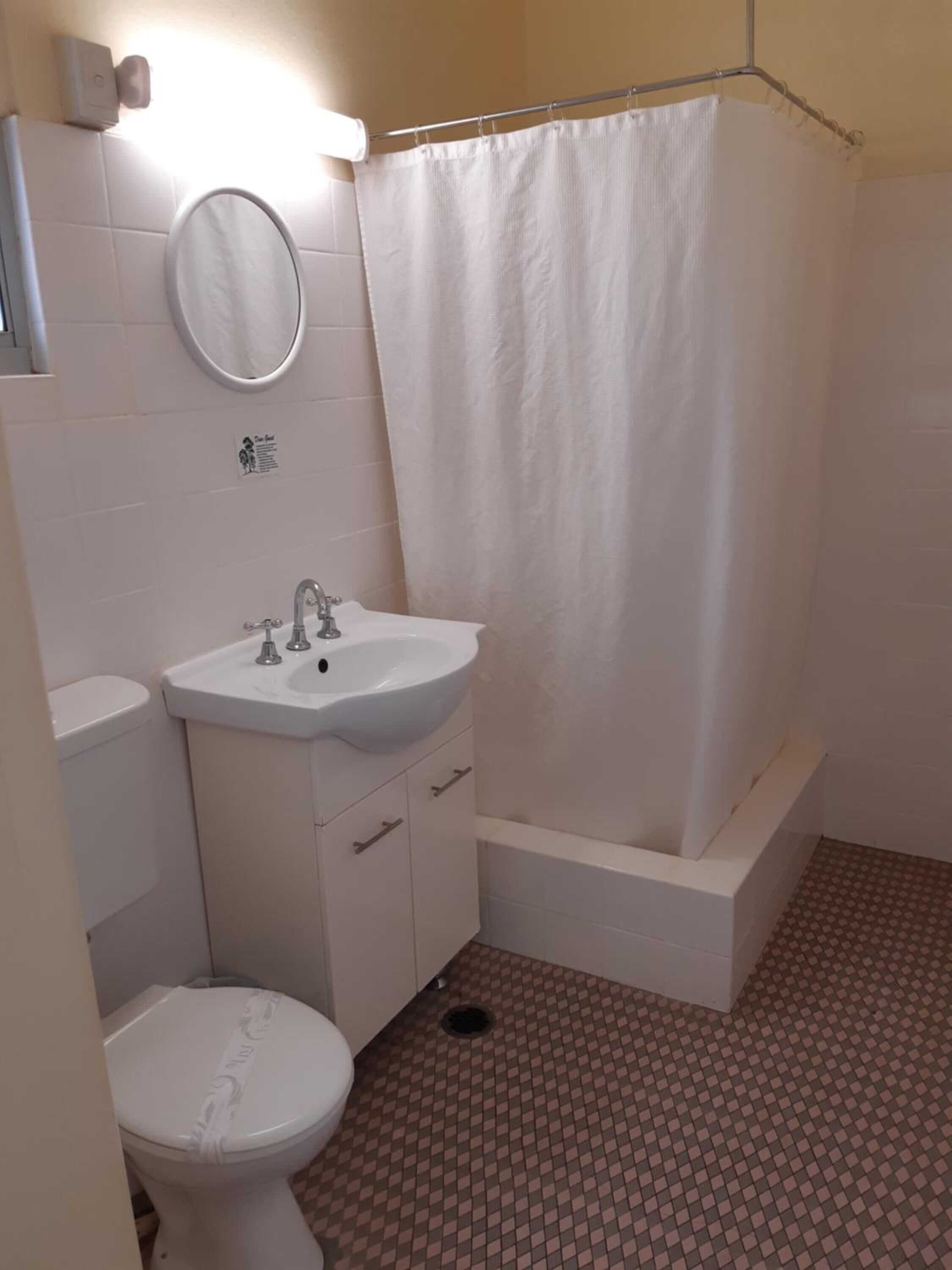 A small bathroom with a toilet, sink, and shower.