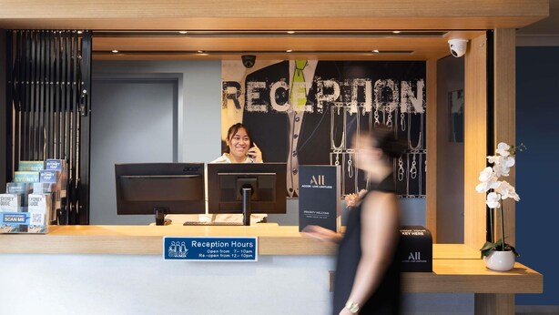 A reception desk with a sign indicating reception hours, a computer, and informational brochures.