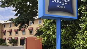 A sign for ibis budget hotels with an arrow pointing left for entry.