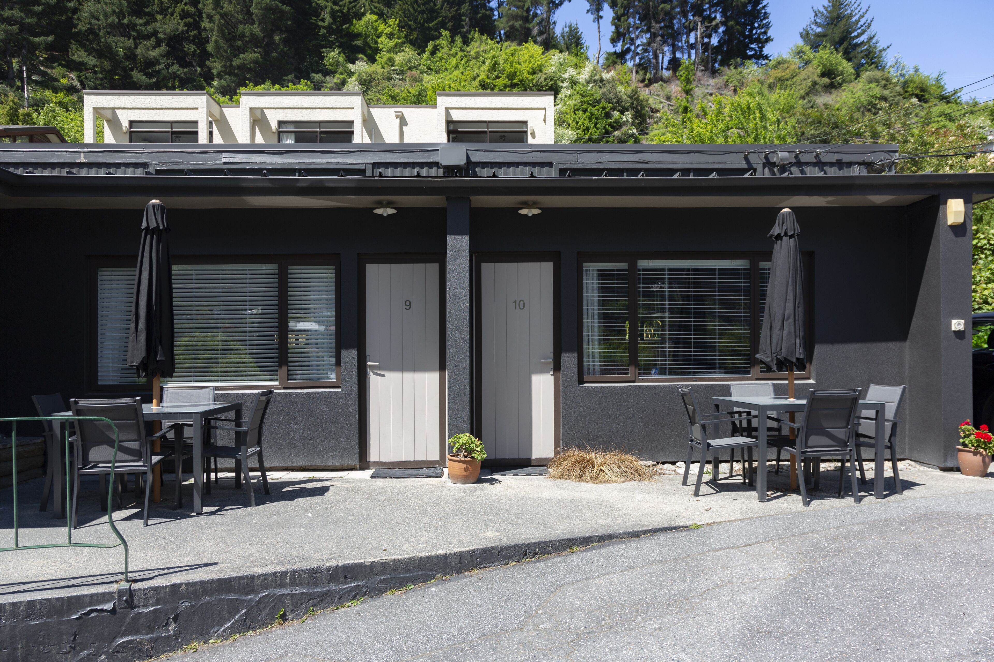 Ein Gebäude mit zwei Hauseingängen, mit den Nummern 9 und 10, und einem Patio mit Tischen und Stühlen.