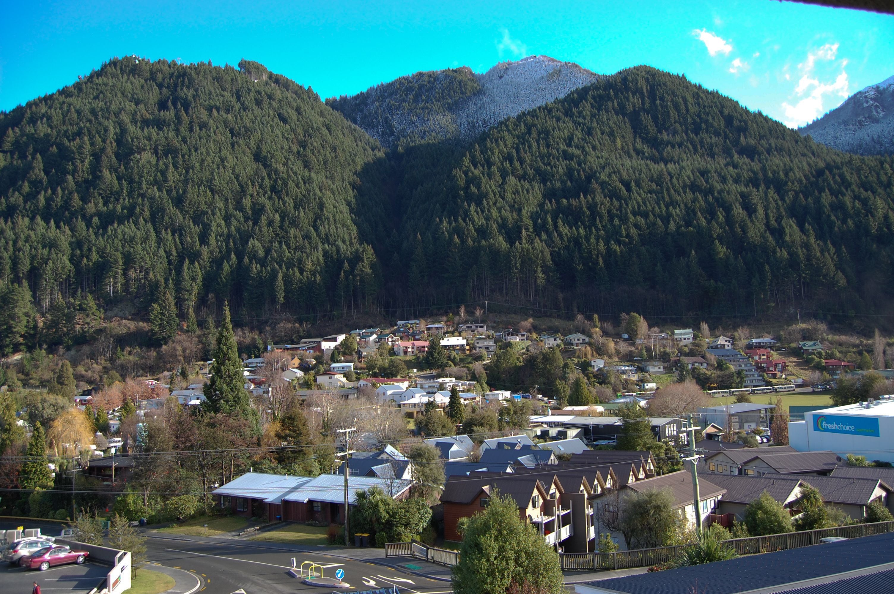 A town with houses and a road in the foreground, surrounded by mountains.