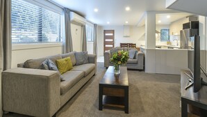 A modern living room with a sofa, coffee table, and a TV. - Abba Court Motel & Apartments (Queenstown)