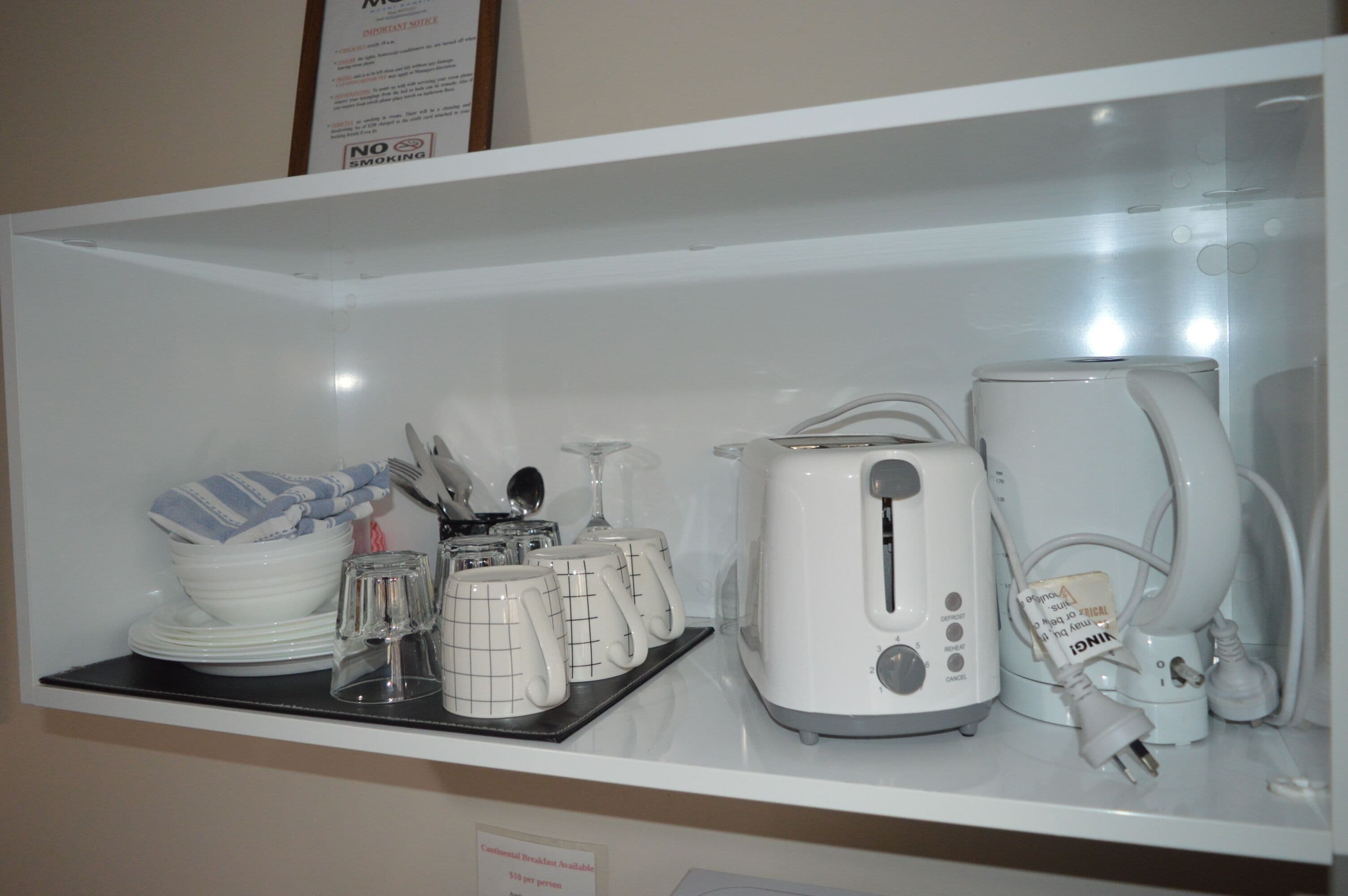 A kitchen area with a toaster, a kettle, and a coffee maker on a countertop.