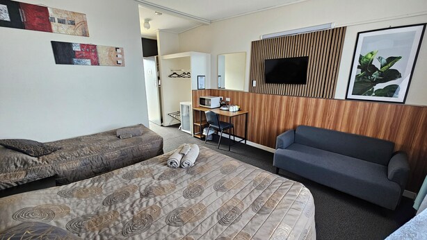 Una habitación de hotel con dos camas, un escritorio, un televisor y un sofá.