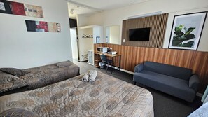 A hotel room with two beds, a desk, a TV, and a couch. - Blue Lake Motel (Mount Gambier)