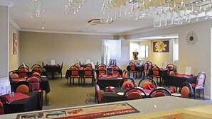 A hotel dining area with tables and chairs, a chandelier, and a sign indicating a restaurant.