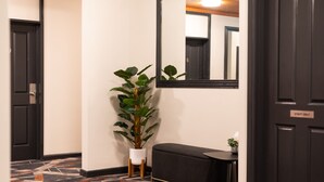 A hallway with a black door labeled "STAFF ONLY," a potted plant, a bench, and a small table with a plant. - Harp Hotel (Wollongong)