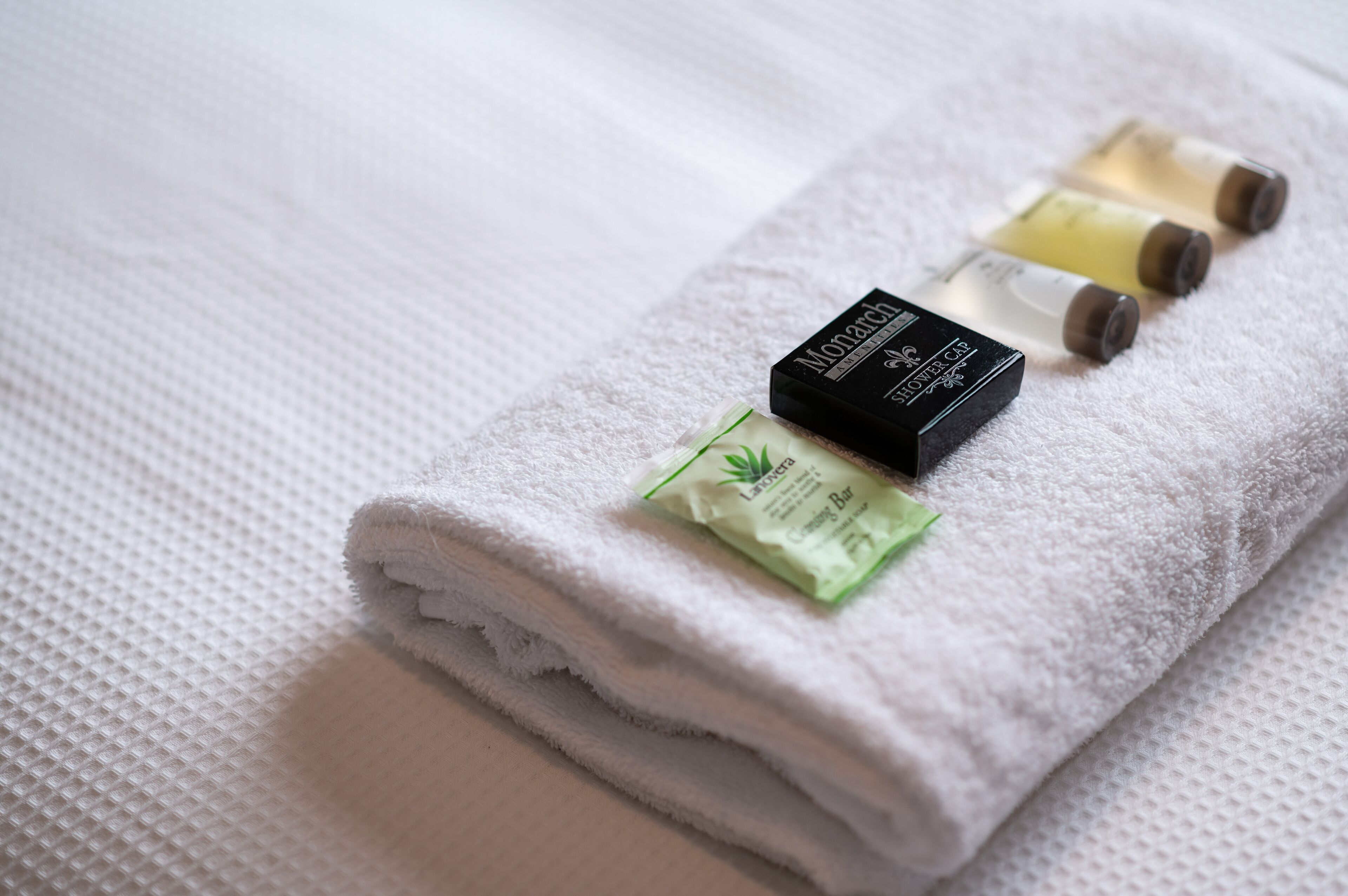 A neatly folded white towel with three small bottles of lotion on it.