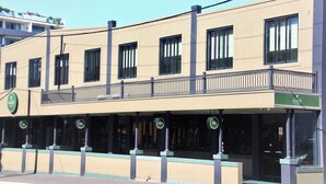 A hotel with a flat facade, multiple windows, and a balcony with a railing. - Harp Hotel (Wollongong)
