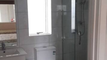 Ein kleines Badezimmer mit Toilette, Waschbecken und Duschkabine aus Glas.