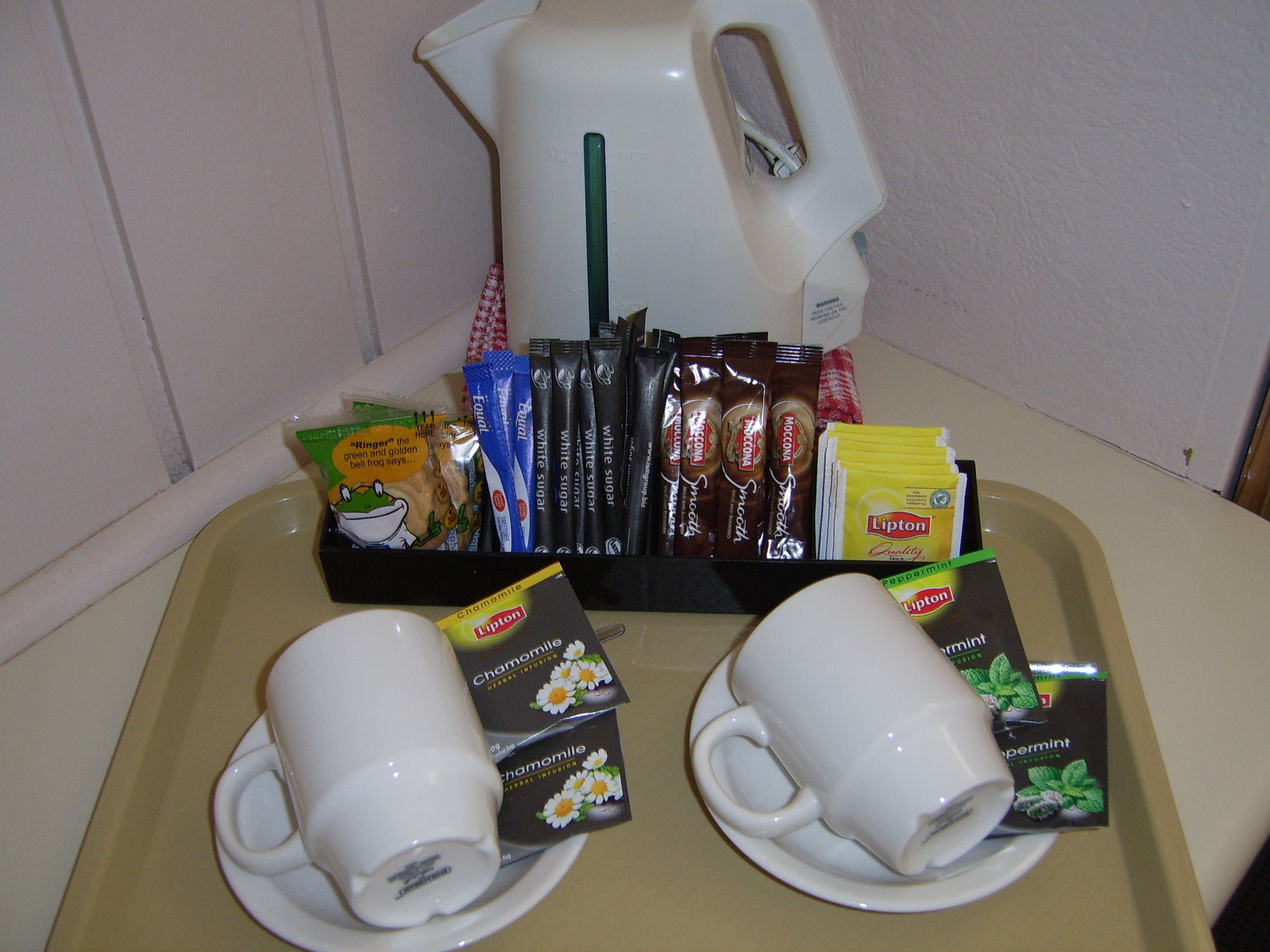 A tray with two white cups, Lipton tea bags, and various snacks.