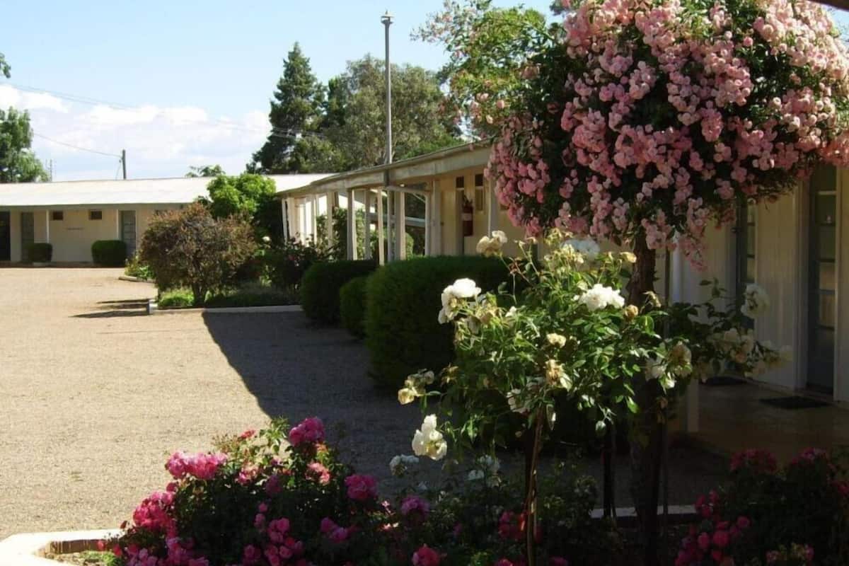 A building with a covered outdoor area, surrounded by well-maintained gardens with various flowering plants.
