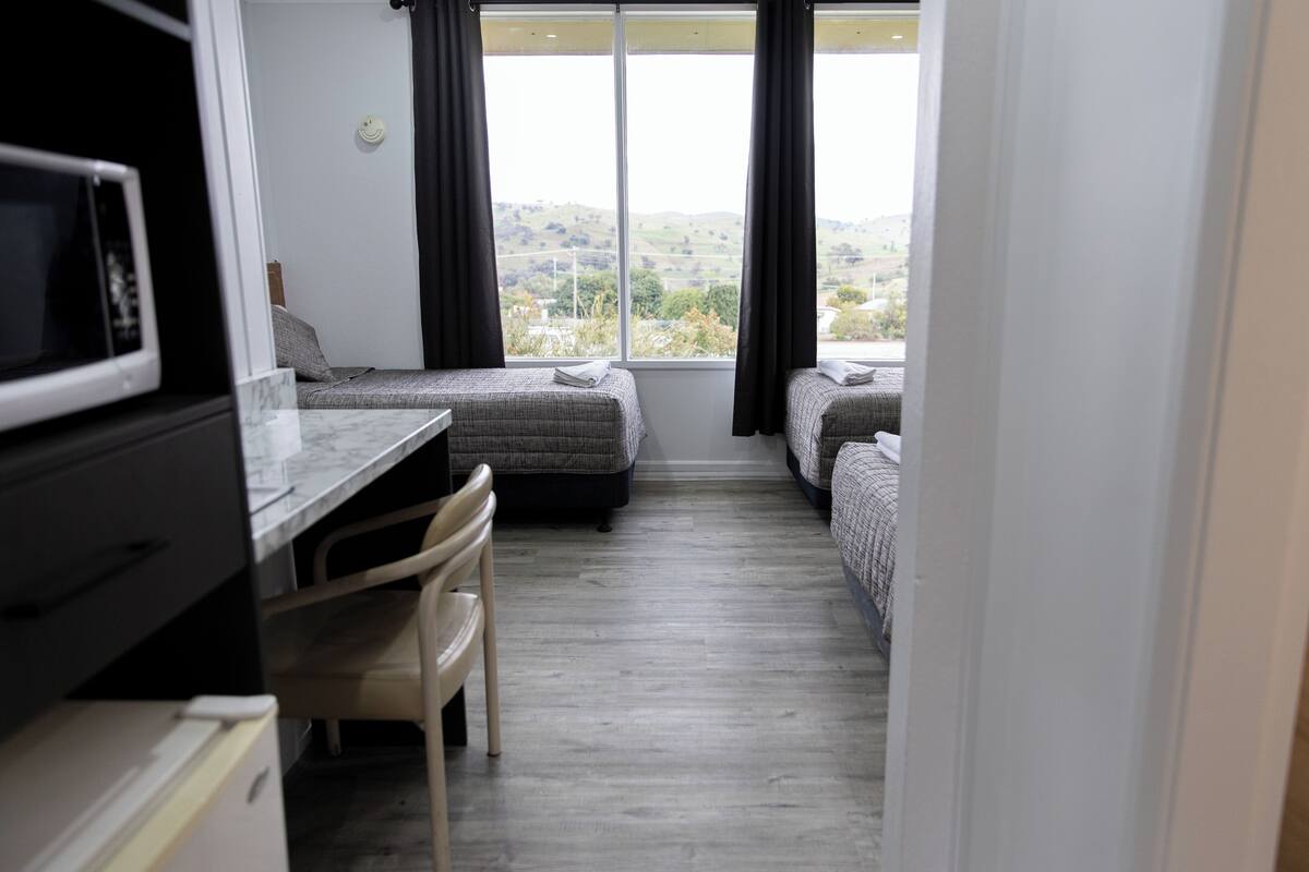 A bedroom with two beds, a desk, and a chair.
