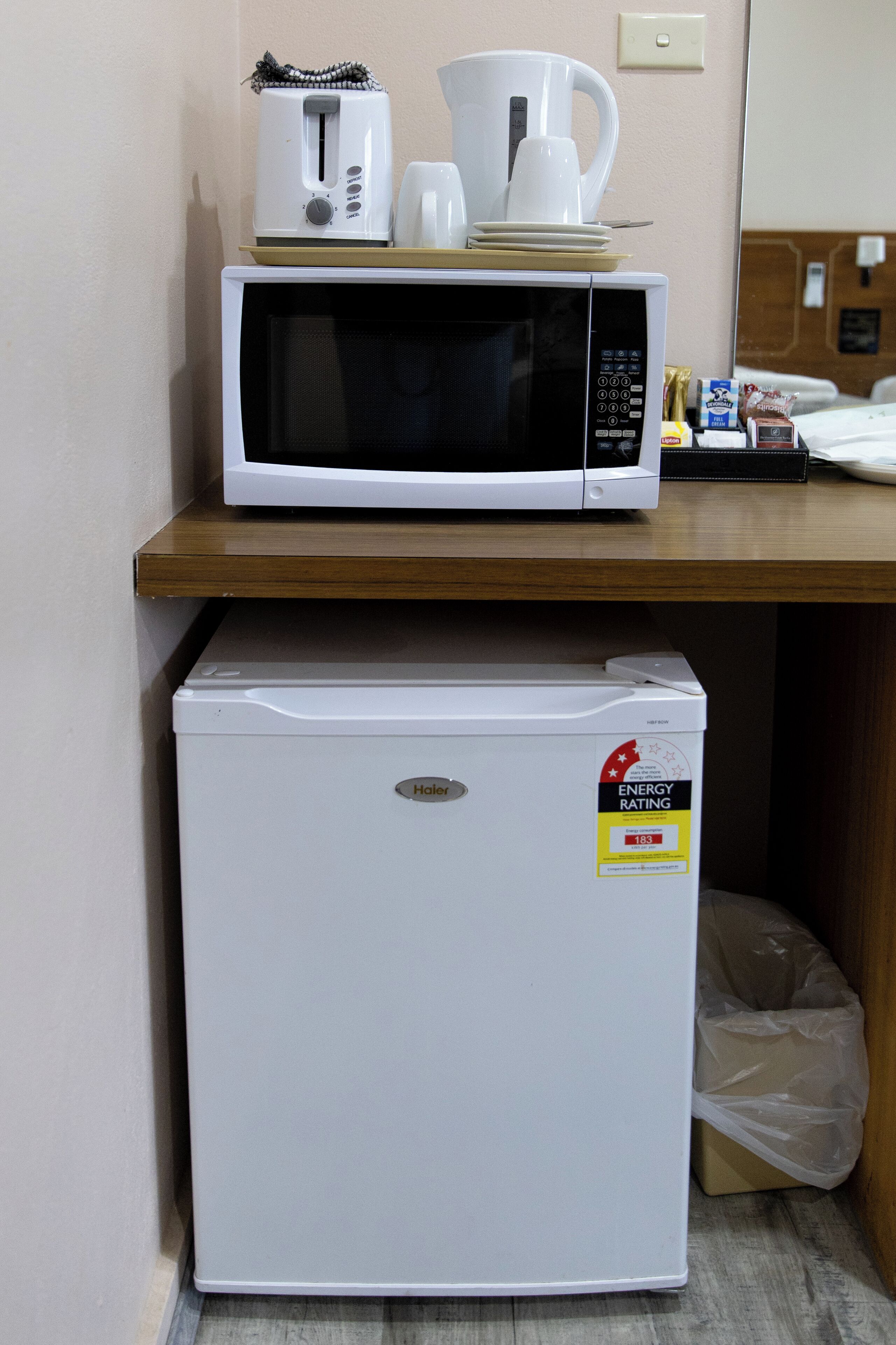 A compact kitchenette with a microwave, toaster, and coffee maker on a wooden countertop.