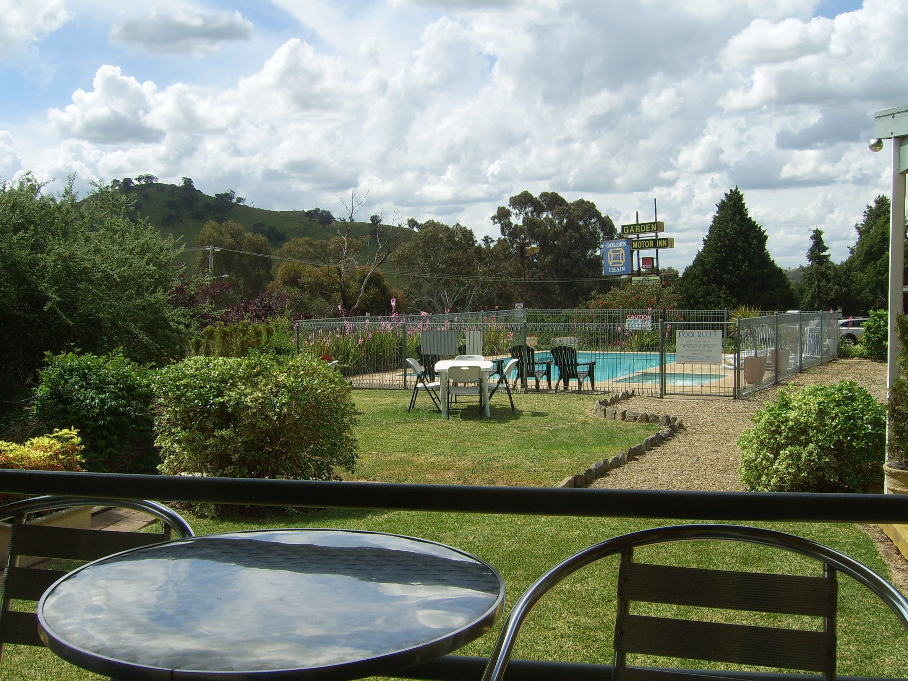A pool area with a fenced pool, lounge chairs, and a table.