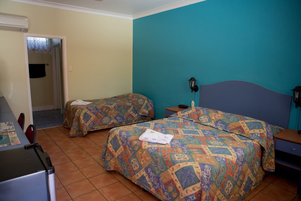 Una habitación con dos camas, un escritorio y la puerta del baño.