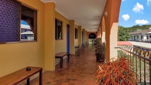 A covered corridor with benches and potted plants, leading to a building entrance. - Adobe Motel (Cairns North)
