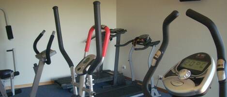 Een sportschool met hometrainers en een loopband.